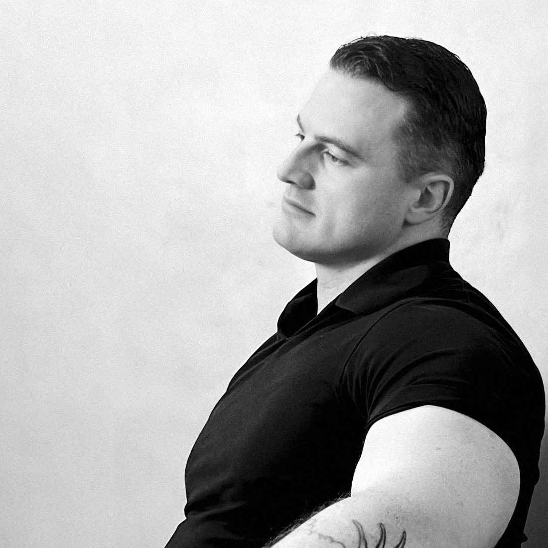 James Richman in profile against a pale wall, looking down to the left.